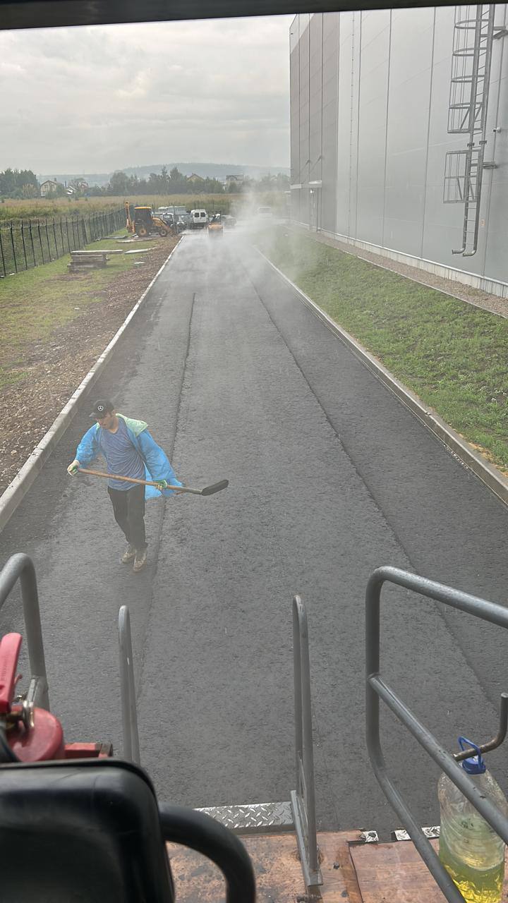 Рабочий выравнивает асфальт